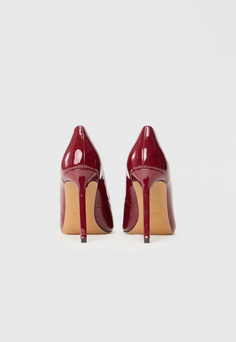 Décolleté in vernice bordeaux con punta affusolata e tacco stiletto sottile. Finitura liscia e lucida con accentuazione della suola beige.