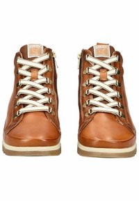 Chaussures montantes en cuir marron avec des lacets texturés blancs et des œillets en métal. Elles présentent une étiquette de logo sur la languette et une semelle en caoutchouc contrastante.