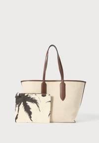 Beige Canvas-Tragetasche mit braunen Lederelementen. Enthält eine abnehmbare Tasche mit einem schwarzen Palmblattmuster auf cremefarbenem Hintergrund.