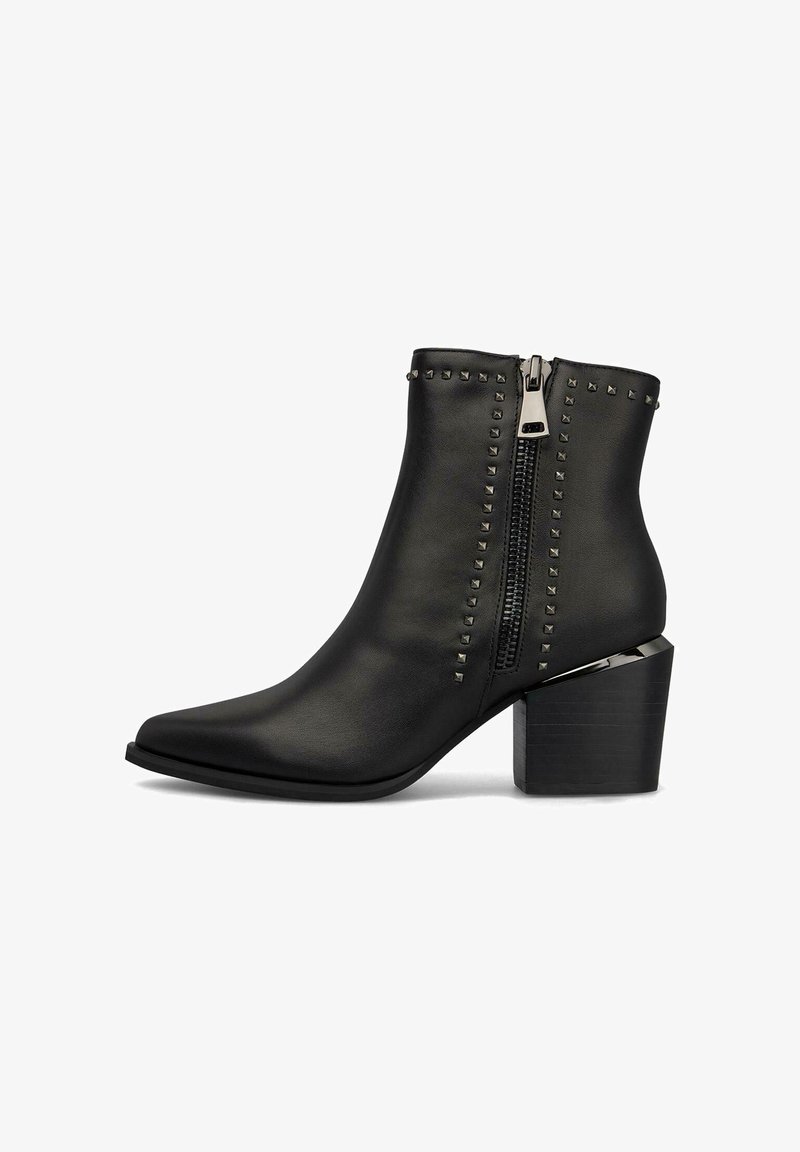 Botas de tobillo de imitación de cuero negro con puntas afinadas, que presentan una cremallera lateral y tachuelas en forma de pirámide a lo largo del shaft. Tacón ancho.