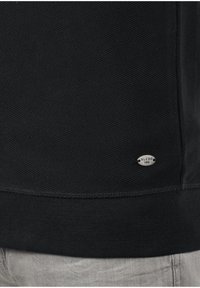 Schwarzer Sweatshirt mit ribbed Struktur, ausgestattet mit einem kleinen silbernen Etikett mit der Aufschrift "BLEND 1993" unten rechts.