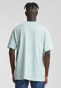 T-shirt vert menthe à manches courtes avec une coupe décontractée, fabriqué en coton doux. Il présente un col rond et une texture lisse. Sans motifs ni accents.