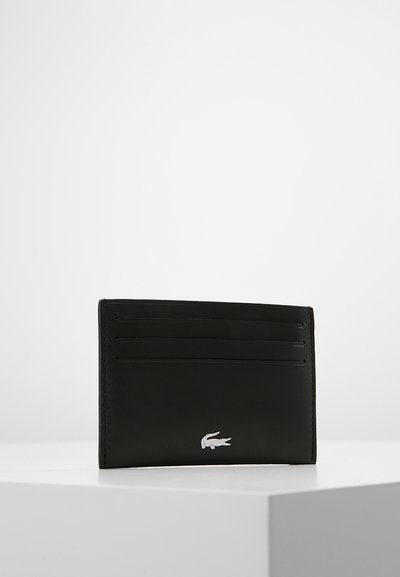 Porte-carte en cuir noir avec six emplacements pour cartes, texture lisse et un petit logo blanc dans le coin inférieur droit. Design minimaliste.