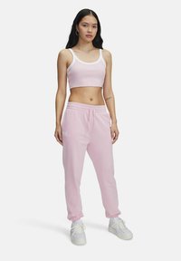 Lichtroze cropped tanktop met witte accenten en bijpassende joggers. De joggers hebben een elastische tailleband en boorden bij de enkels.
