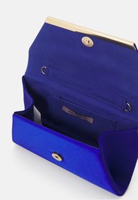 Clutch in satin blu con chiusura dorata, tasca interna e etichetta con logo. Presenta una texture liscia e una forma strutturata. Si apre dalla parte superiore.