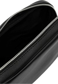 Pochette in pelle nera con una zip argentata, caratterizzata da una texture liscia e un interno pulito. Apertura con zip nella parte superiore per un facile accesso.