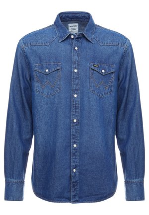 Camisa de mezclilla abotonada en azul oscuro con mangas largas, dos bolsillos en el pecho y costuras en contraste en un patrón de zigzag. Diseño de cuello clásico.