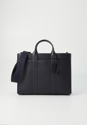 Mallette en cuir noir avec deux poignées, une bandoulière amovible et une petite poche avant sur un fond blanc uni.