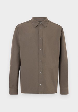 Cămașă maro cu mâneci lungi, guler ascuțit, închidere cu capse și design minimalist. Materialul pare neted, cu finisaj mat.