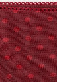 Tissu rouge transparent avec des pois rouges vifs et un bord festonné décoratif avec des détails découpés.