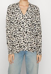 Blusa a maniche lunghe in tessuto leggero con base crema, caratterizzata da una stampa astratta in nero e grigio, scollatura a V e vestibilità rilassata.