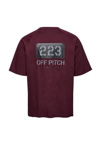 Burgundy t-shirt med kort ärm, som har en rektangulär grafik med "223 OFF PITCH" i vit och grå text på baksidan. Material av bomull.