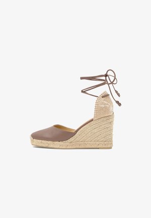 Zapato espadril de cuña marrón con suela de yute trenzada, punta cerrada, detalle beige tejido en el talón y cordones marrones para atar en el tobillo.