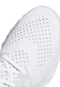 Gros plan sur une chaussure de sport blanche en maille tricotée avec une tige en mesh respirant et des lacets blancs noués en nœud.