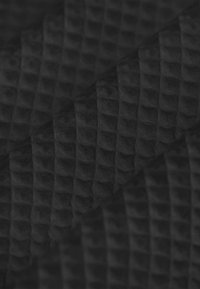 Schwarzer, strukturierter Stoff mit einem Rautenmuster, das ein erhaben gestaltetes, waffle-artiges Design aufweist. Weiches und strapazierfähiges Material, das Tiefe und Dimension betont.