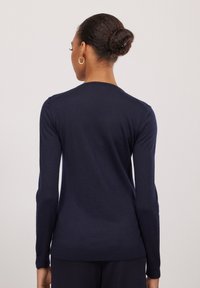 Marineblaues Langarmpullover mit einer taillierten Passform, geripptem Saum und glatter Textur. Der Rücken weist einen hohen Kragen und ein einfaches Design auf.