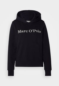 Czarna bluza z kapturem wykonana z bawełny, z kieszenią typu kangur i ściągaczami na mankietach. Napis wyświetlony na przodzie brzmi "Marc O'Polo" w jasnym kolorze.