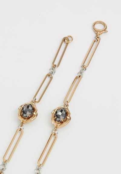 Gold and silver linked chain with large black faceted oval gemstones set in gold floral-style bezels on white background.