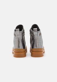 Botas de tobillo de metal plateado con un acabado de cuero texturizado, punta redonda y una suela de goma marrón resistente; cuenta con cremallera lateral y detalles de costura.