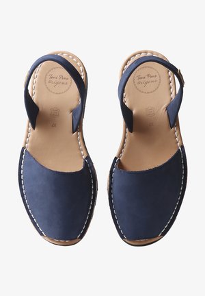 Námořnické kožené sandály s kulatou špičkou, otevřenou zadní částí a kotníkovým páskem. Bílé švy podél podrážky. Hladký povrch.