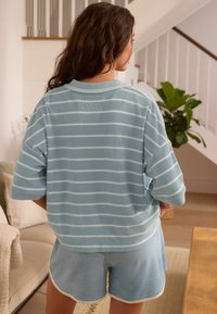 Hellblau gestreifter Fleece-Top mit kurzen Ärmeln, kombiniert mit passender Shorts, aus weichem Material und mit weißen Besatzdetails.