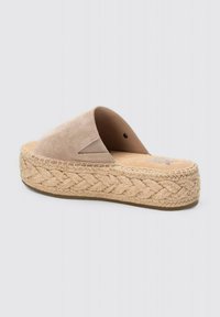 Sandal de ante beige con un diseño amplio y abierto, y una suela de plataforma de yute trenzado, que presenta un patrón trenzado texturizado alrededor de la base.