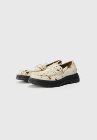 Beige loafers dengan bagian atas yang bercorak tekstur dan sol karet hitam. Memiliki ujung bulat dan detail jahitan.