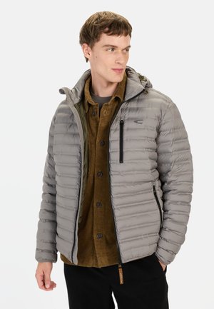 Letvægts grå pufferjakke med horisontal quiltning, hætte og lynlåslommer, lagd ovenpå en brun corduroy skjorte.