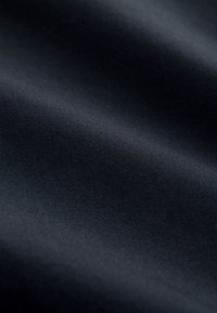Tissu noir lisse avec une texture de tissage diagonal subtile et des plis doux créant des ombres douces.