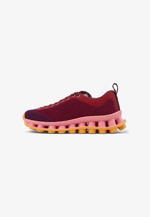 Zapatillas deportivas con parte superior de malla a rayas en tonos granate y rojo, entresuela rosa y suela exterior amarilla con un diseño segmentado único.