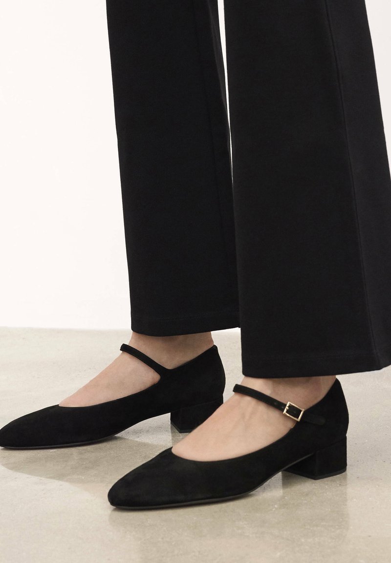 Scarpe Mary Jane in suede nero con punta affilata, tacco basso a blocco e una cinghia alla caviglia regolabile con una piccola fibbia in metallo.
