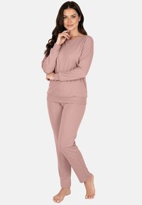 Rózsaszín kényelmi ruhaszett hosszú ujjú, kerek nyakú felsővel és hozzáillő, karcsúsított nadrággal. Puha, sima tapintású anyagból.