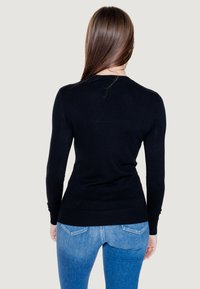 Maglione nero a maniche lunghe con un design aderente e orlo a costine. Il materiale sembra morbido e liscio, con uno stile minimalista.
