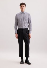 Koszula w kratę w niebiesko-białym kolorze, zestawiona z czarnymi spodniami w kant i czarnymi skórzanymi butami. Gładki materiał, dopasowany krój.