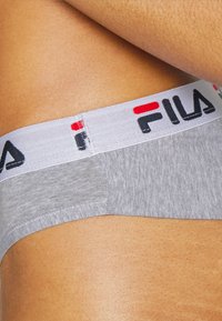 Sivi pamučni donji veš s bijelim elastičnim pojasom na kojem se nalazi crno-crvena FILA marka. Tkanina ima mekan i glatki osjećaj.