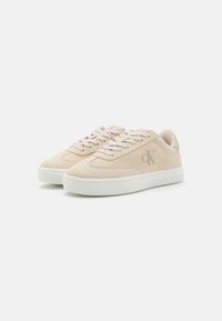Beige semskinn-sneakers med rund tå, hvit gummisåle og tonale snører. Har en subtil preget logo på siden.
