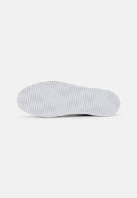 Talpa de pantof alb din cauciuc, cu un model texturat de striții orizontale, detalii cu logo și margini netede.