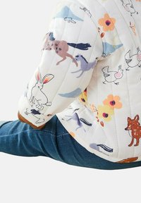 Kurtka pikowana w kolorze białym z kolorowymi wzorami zwierząt i kwiatów. Posiada miękką teksturę oraz brązowe akcenty na mankietach.