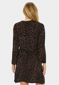 Vestido de estampado de leopardo con una combinación de colores marrón y negro, mangas largas, cintura ajustada y una falda ligeramente acampanada.