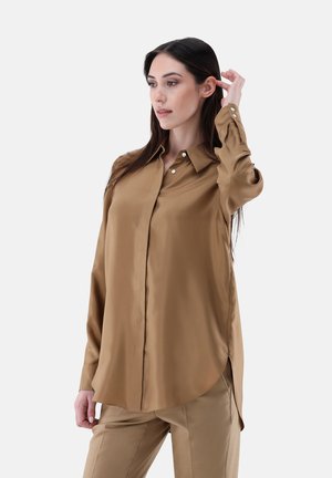 Brown satin shirt with a classic collar, long sleeves, button details, and a curved hem, paired with matching tan trousers.