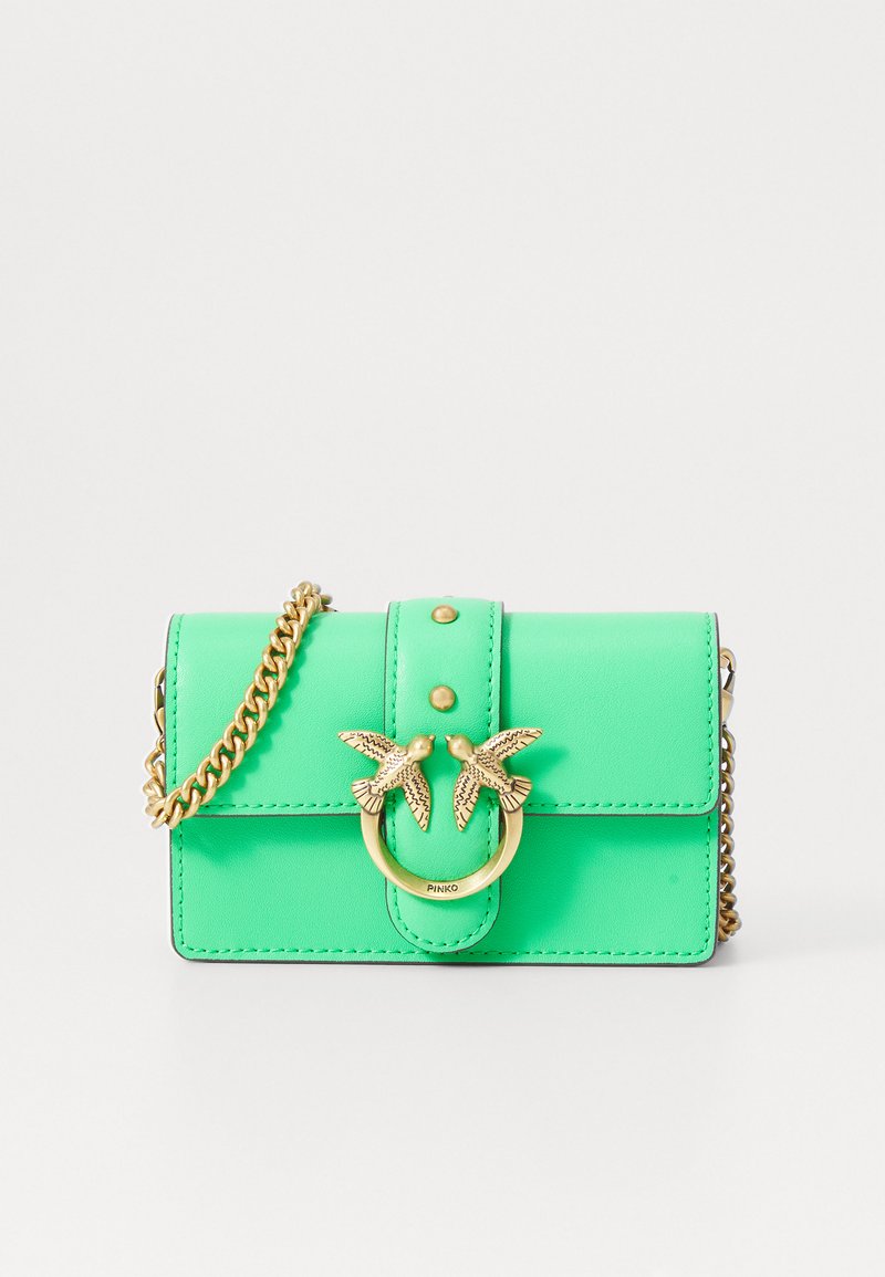 Zelena kožna crossbody torba s preklopom, zlatnim hardverom, ukrasom u obliku ptice, lance za nošenje i ukrasnim šavovima.