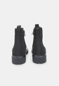 Botine negre până la glezne, din suede, cu ținte decorative pe laturile exterioare, au talpa din cauciuc negru și fermoare pe lateral pentru a fi ușor de purtat.