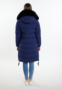 Námornícky puffer kabát s umělým kožíškem na límci, s prošívaným designem, kapucí a zipy na lemu. Nositý přes džíny a tenisky.