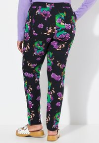 Des leggings noirs ornés d'un motif floral violet vibrant et de dragons verts. Ils ont une coupe ajustée avec une texture lisse et une taille élastique.