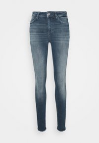 Jeans ajustados de denim azul medio. Presentan un diseño de cinco bolsillos, lavado desgastado y dobladillo sin acabar en los tobillos. Cierre frontal con botón y cremallera.