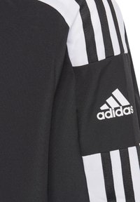 Schwarze Sportjacke mit weißen Streifen an den Ärmeln, aus strukturiertem Material, mit einem auffälligen weißen Adidas-Logo auf dem Arm.