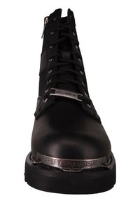Bota de motocicleta de cuero negro con un caño alto, punta redonda, detalles de correa de metal y un prominente sistema de cordones en la parte frontal.