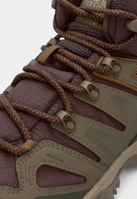 Maronnfarget tursko med teksturert syntetisk materiale, brune snøringer og beige detaljer, med en støttende ankelkrage og solid såle.