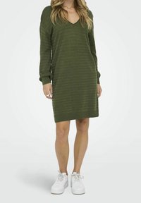 Robe en maille vert olive à manches longues, col en V, texture rayée, poignets côtelés et coupe décontractée, portée avec des baskets blanches.