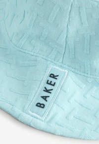 Gorra de cubo azul claro con un patrón texturizado, con etiqueta bordada 'BAKER'. Tela suave con un acabado liso.